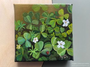 Dipinto olio su tela di 10x10 cm raffigurante una piccola coccinella rossa su un prato di trifogli.